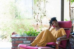 Woman in yellow dress relaxing with eyes closed on garden patio
