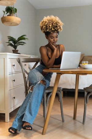 Black woman with laptop sitting on chair during breakfast