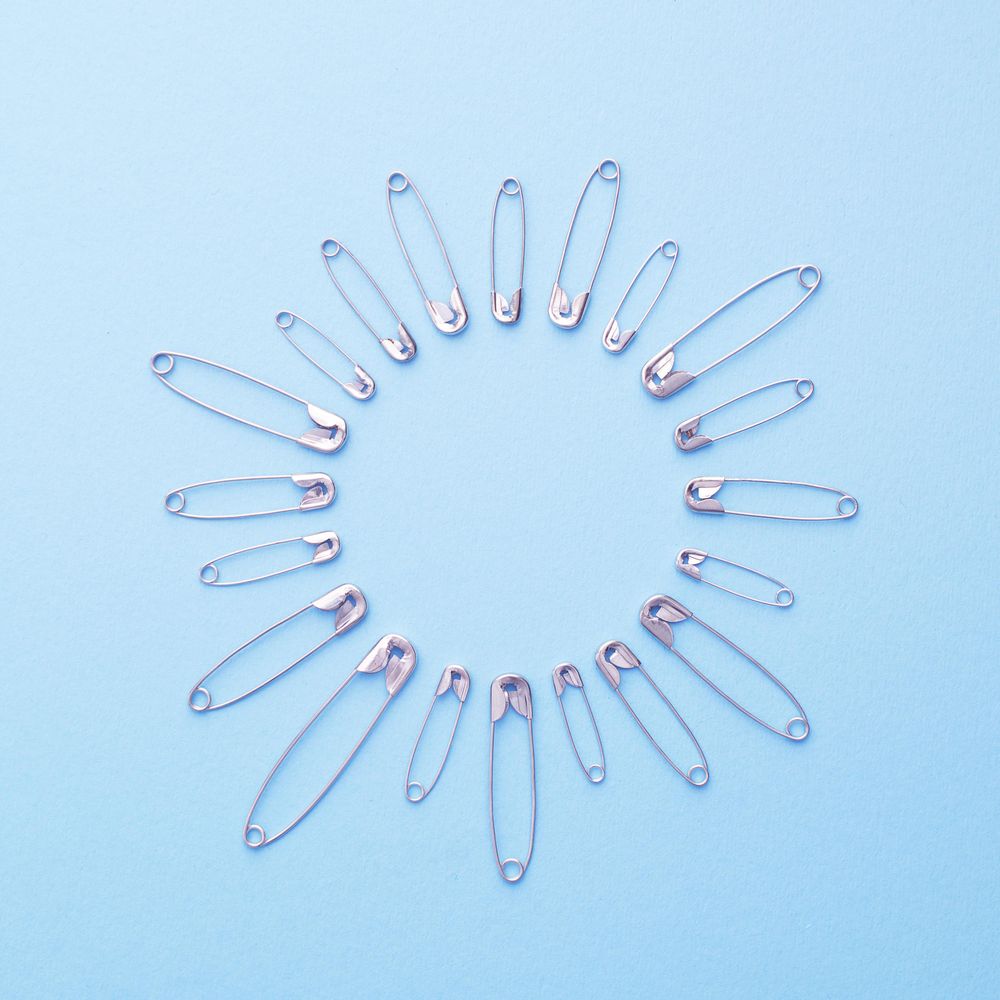 Safety pins in a circle shape over blue background