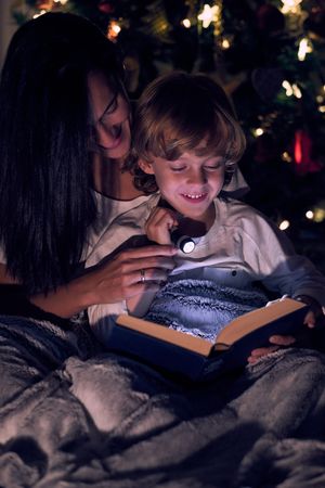 Mother reading book with son in dark room