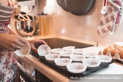 Cropped image of woman preparing paper cups for muffins 5rKYd4