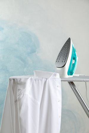 Iron and shirt on ironing board, space for text