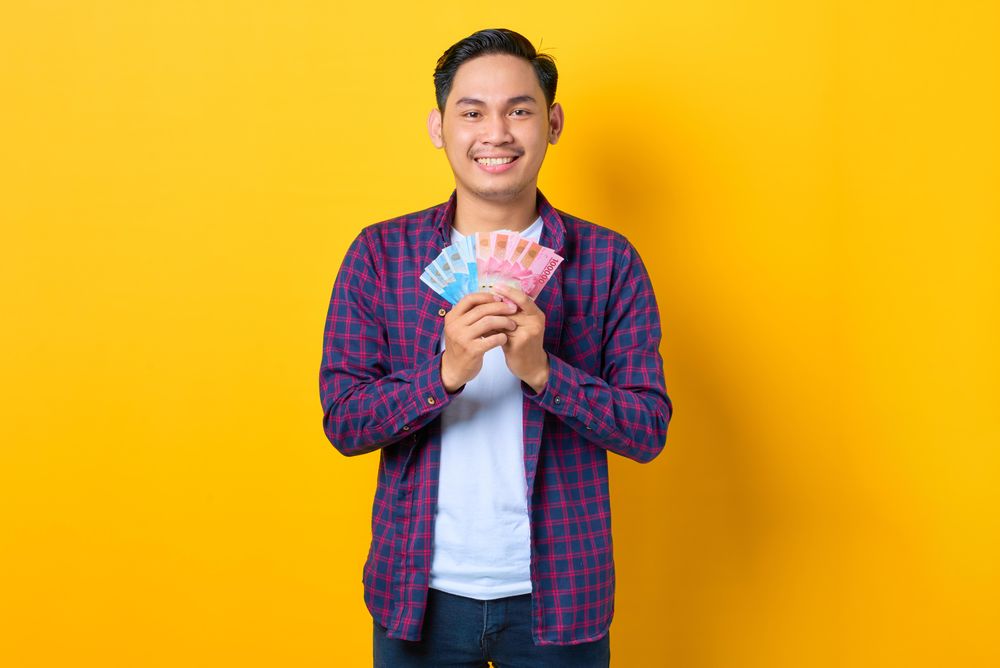 Happy Asian man holding up a fan of cash