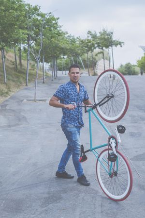 Male in jeans holding bike up vertically