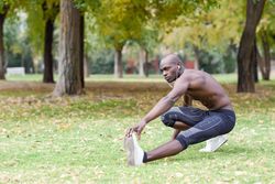 Male warming up with shirt off listening to music on headphones