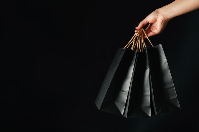 Female hand hold paper bags on dark background