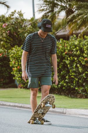 Young man in green shirt with a hat skateboarding outdoor