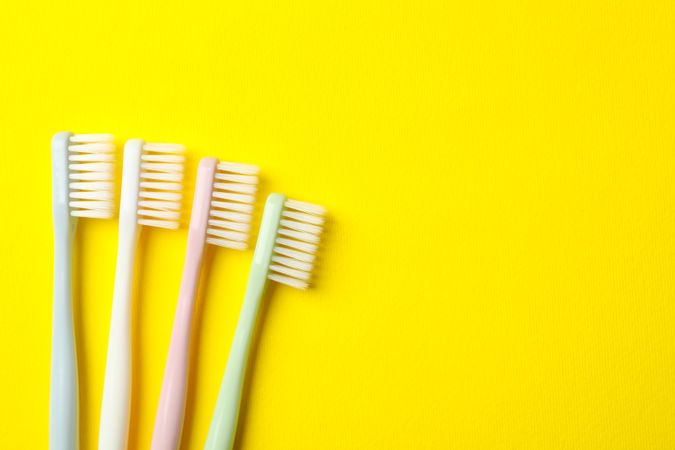 Toothbrushes on yellow background, space for text