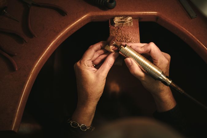 Close up of female jeweler hands polishing a ring at her workbench