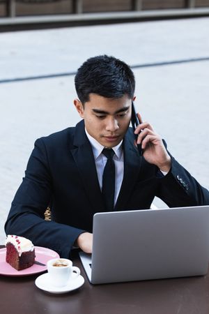 Cheerful Asian businessman working in cafe