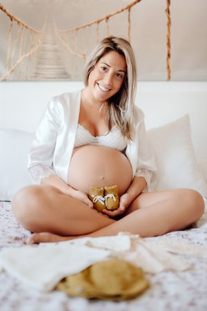 Pregnant woman demonstrating baby clothes