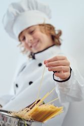Preteen boy touching spaghetti stick in saucepan