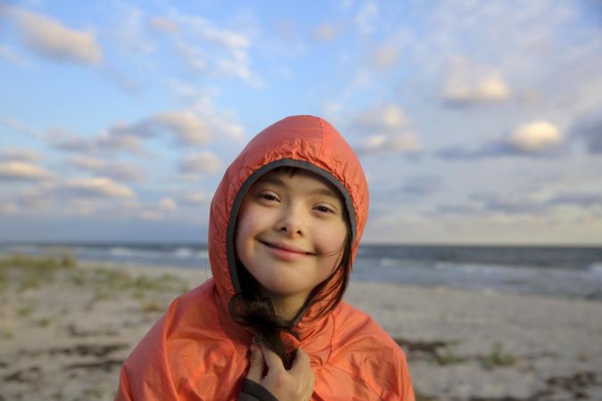 Happy young child smiling at camera with beach in the background