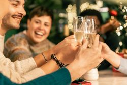 Group of friends making a joyful toast with champagne at a Christmas party.