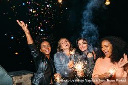 Multi-ethnic group of fun women celebrating at a party with sparklers 0LAQg5