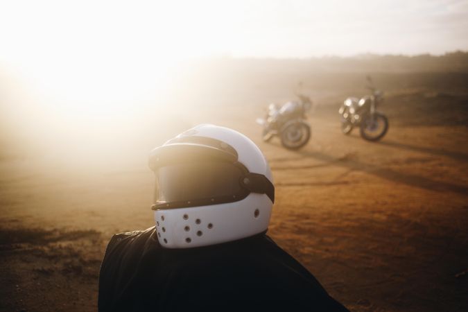 Biker helmet on dusty path with two bikes in background