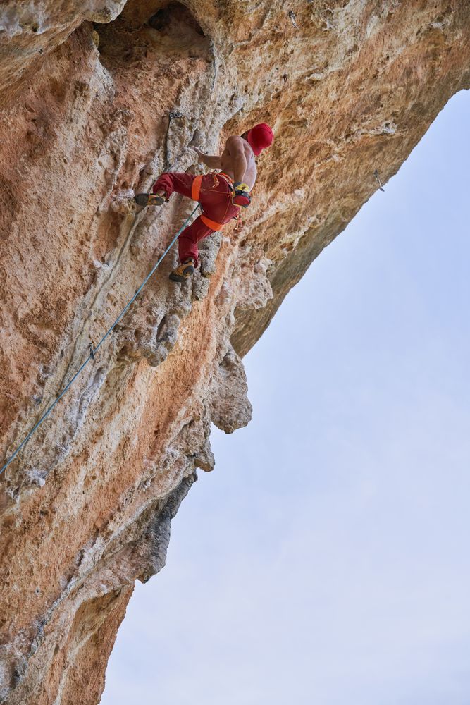 Anonymous strong man climbing on rock in mountains