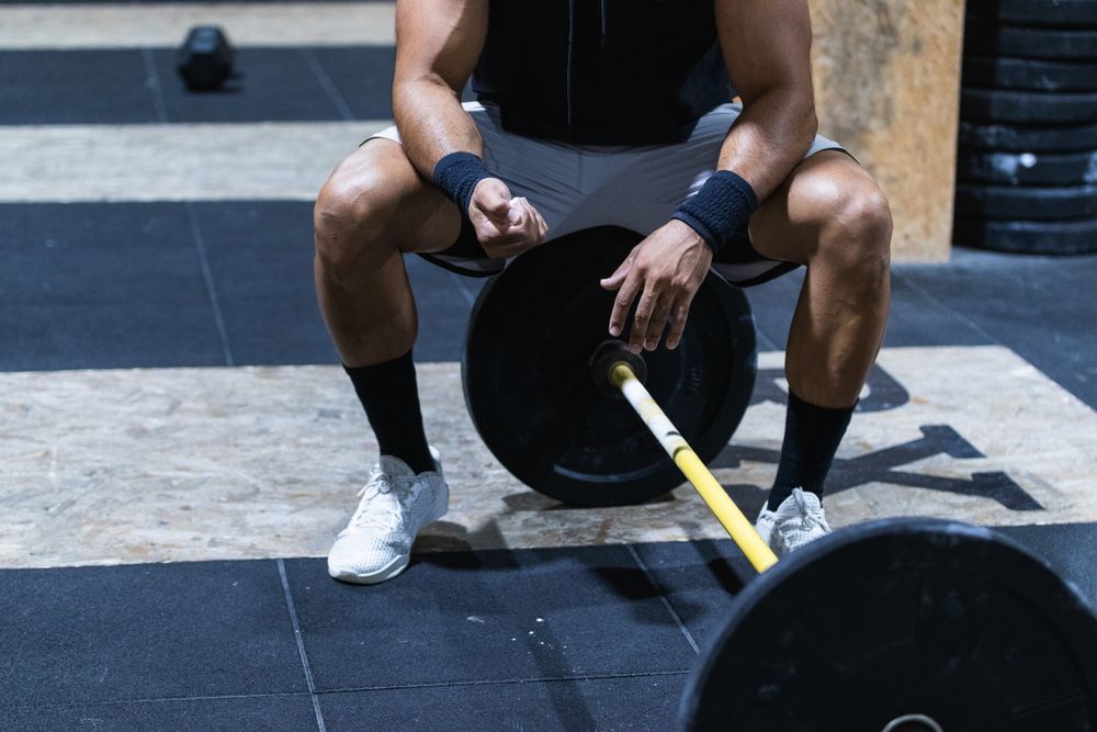 Strong anonymous sportsman near barbell