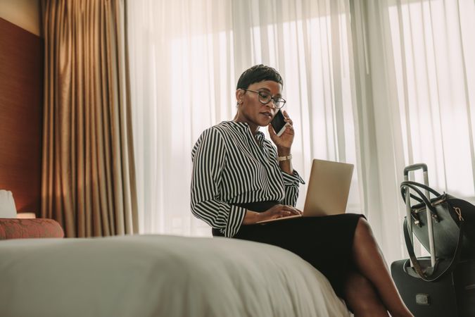 Businesswoman working with laptop computer and mobile phone in hotel room