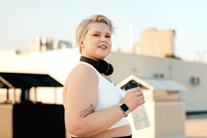 Blonde woman in exercise gear with headphones and a water bottle