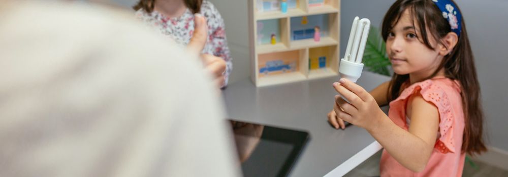 Student showing led lamp to female teacher in ecology classroom