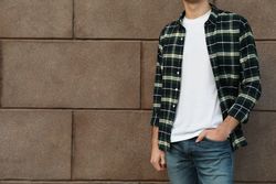 Men in t-shirt and checkered shirt against building, copy space