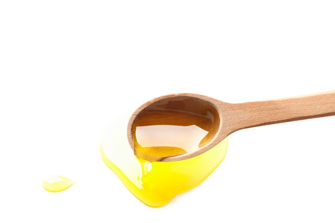 Wooden spoon with honey isolated on plain background, closeup