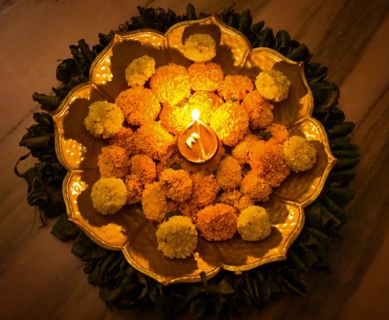 Top view of Diya surrounded by marigold flower on tray