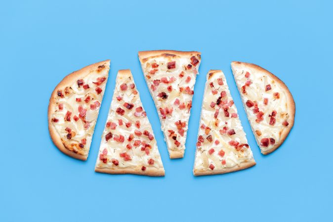 Sliced Tarte flambee above view, isolated on a blue background