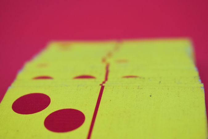 Red and yellow domino cards on red table with copy space