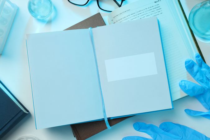 Books, notepads, flasks and gloves on light background, top view