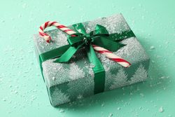 Christmas box with candy cane on mint background with snow
