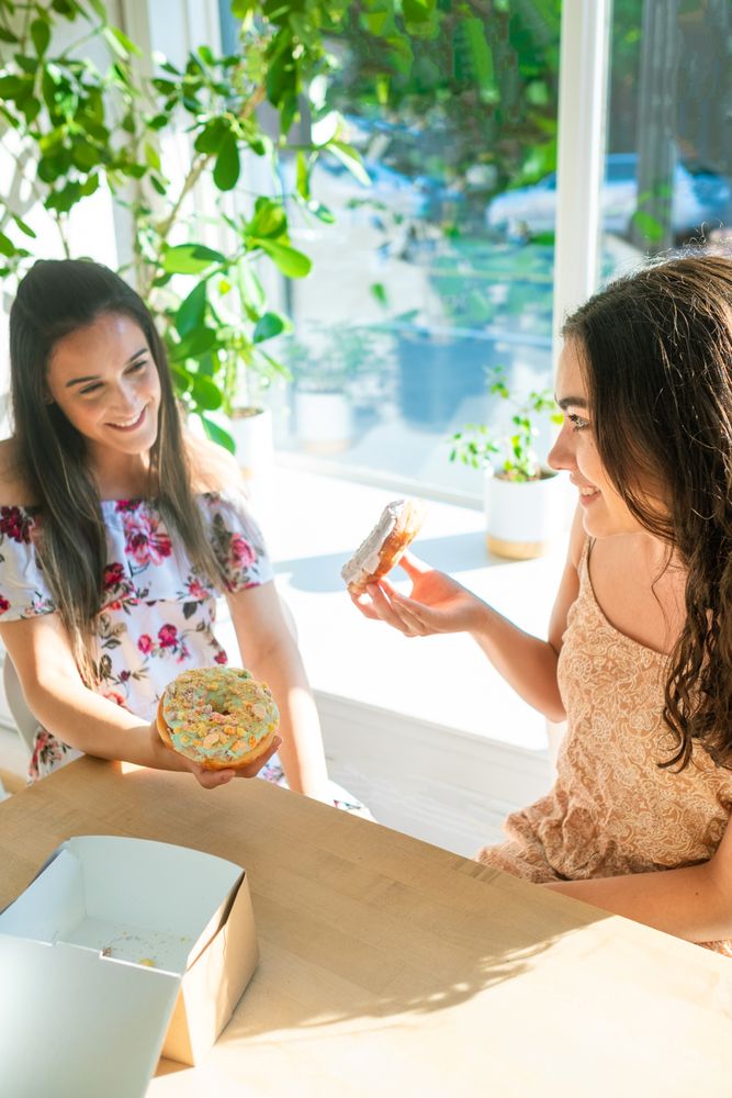 Joyful female friends eating donuts at cafe