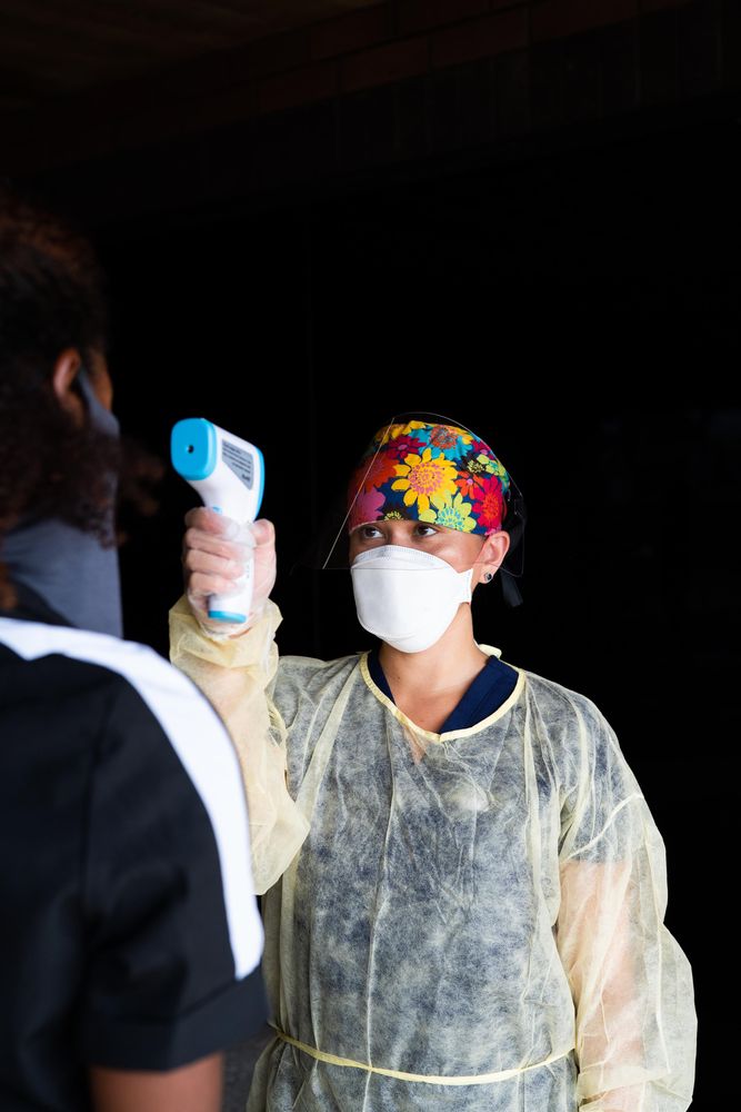 Nurse in PPE taking temperature with infrared thermometer