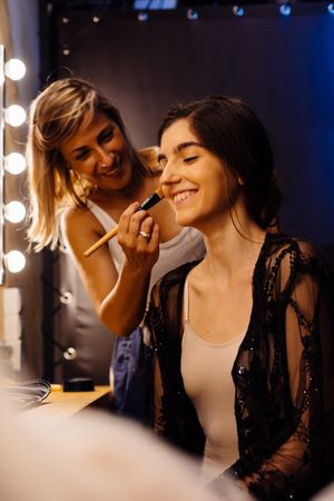 Makeup artist doing makeup for young female artist