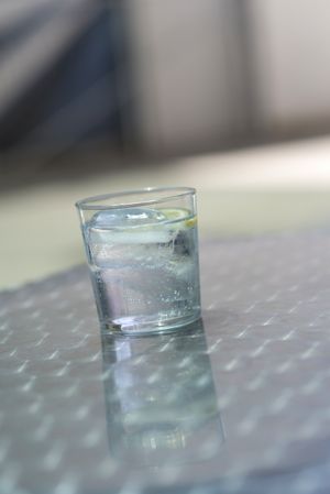 Glass of water with ice on a silver table outside