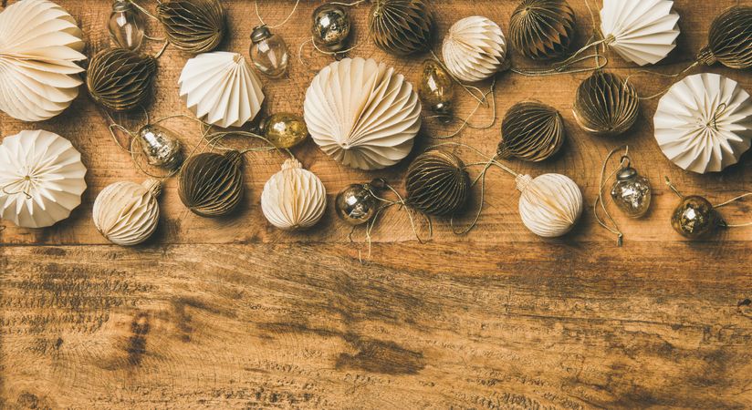 Gold and cream folded tree ornaments, and baubles on wooden board, copy space