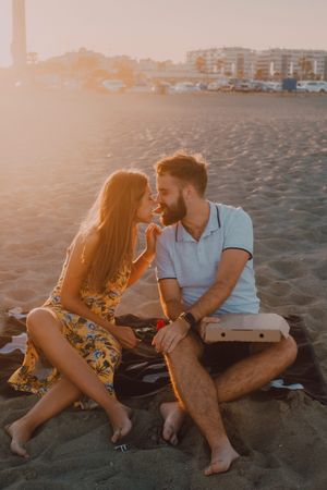 Lovely couple eating together at sandy beach