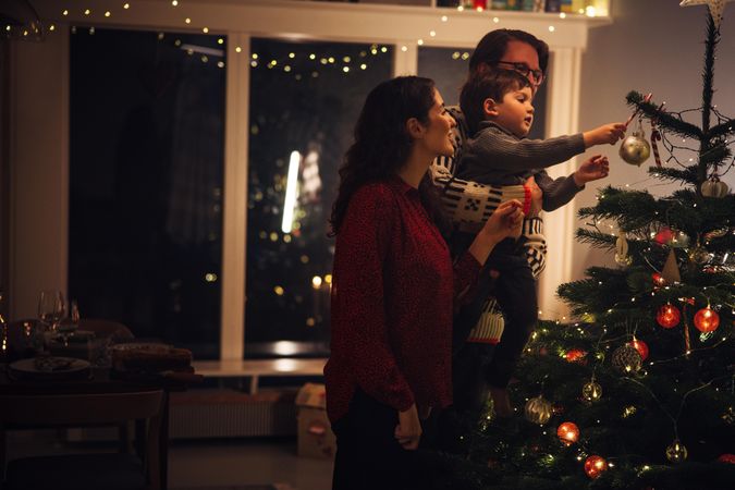 Small family decorating Christmas tree together at home