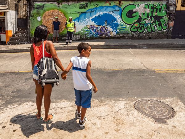 Rio de Janeiro, Brazil - February 13 2014: Mother with son standing near shabby road on street