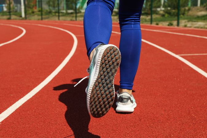 Girl running on red athletic track. Sport concept