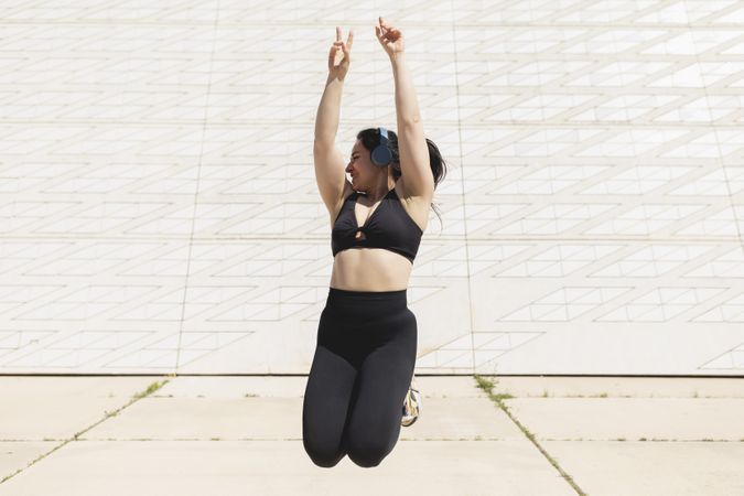 A happy young woman jumps in the air, while listening to music and enjoys a time of sport and disconnection