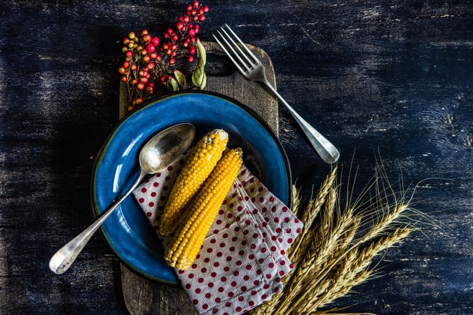 Top view of autumn table setting with polka dot napkin, corn, wheat and berry garnish