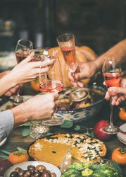 Group of people at festive fall dinner toasting with wine over pie