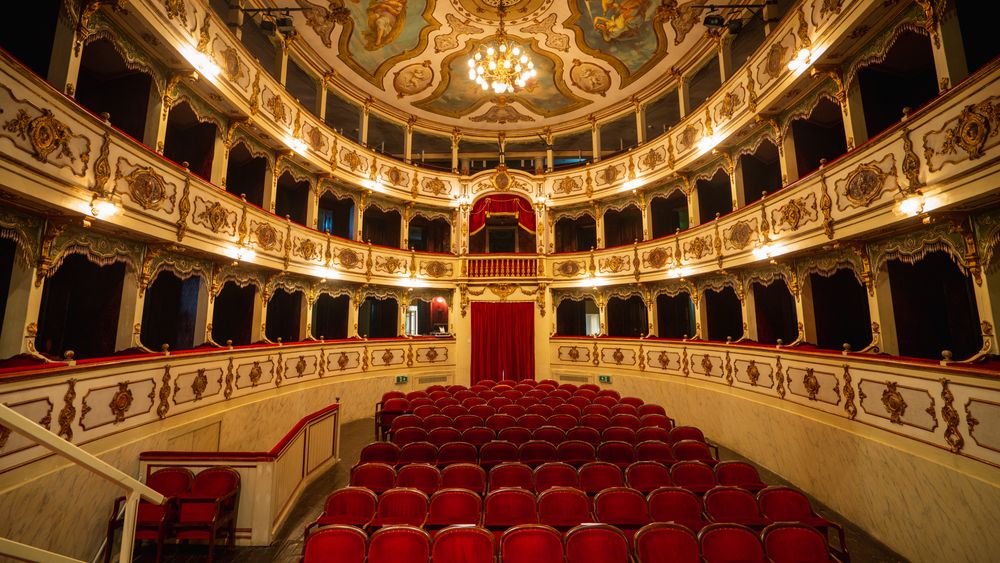 Wide shot of an Empty Elegant Classic Theatre with Red Velvet Chairs and Curtains.