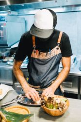 Chef with mask putting plate together in kitchen