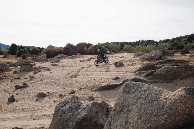 Motorcyclist on rugged off-road track with shrubs