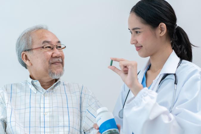 Older man smiling with medical professional holding medicine for him to take