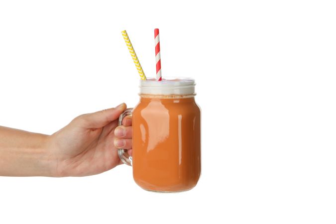 Female hand hold glass jar of pumpkin latte, isolated on neutral background