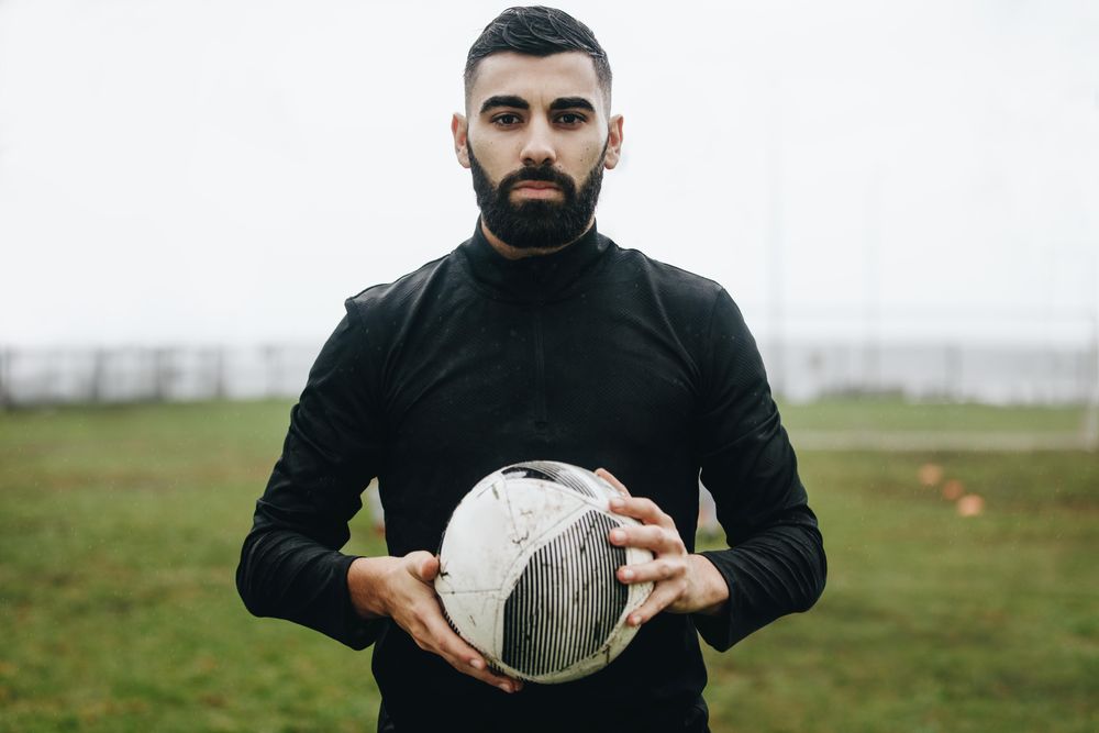 Football Player Holding Football With Both Hands Stock Photo